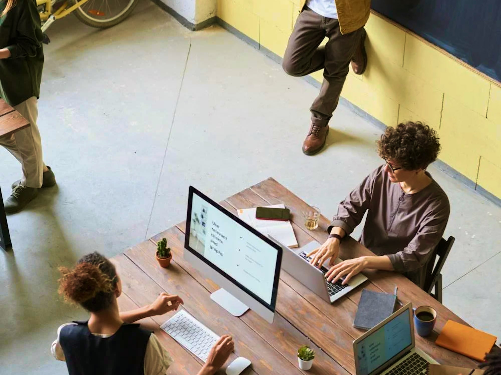 Overhead view of students studying at a wooden table with laptops and notebooks