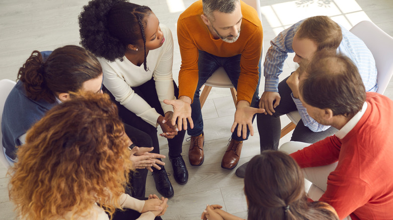 Overhead photo of diverse group seated in a circle, talking and gesturing